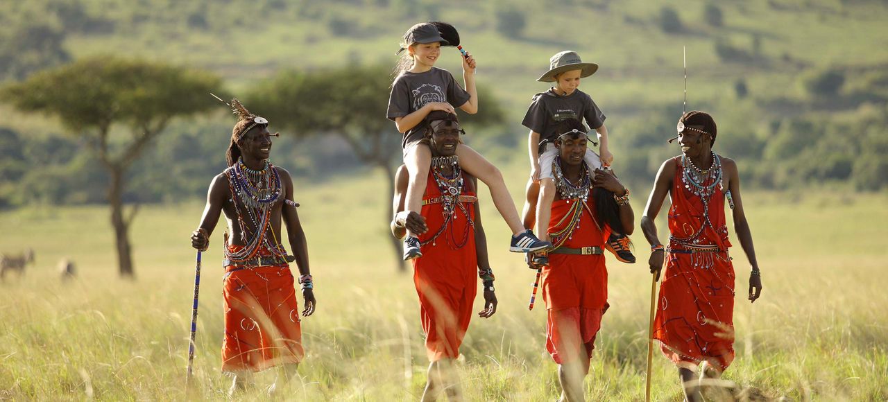 Children walking across the grassland with Maasai guides