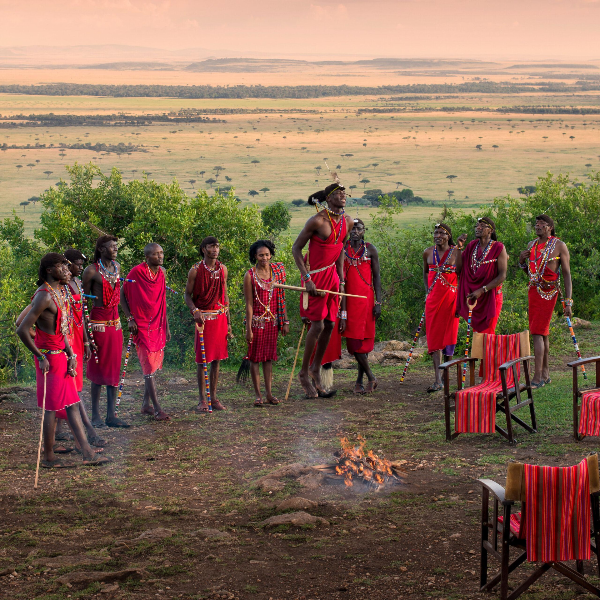 Maasai warriors singing and jumping around a fire above the plains