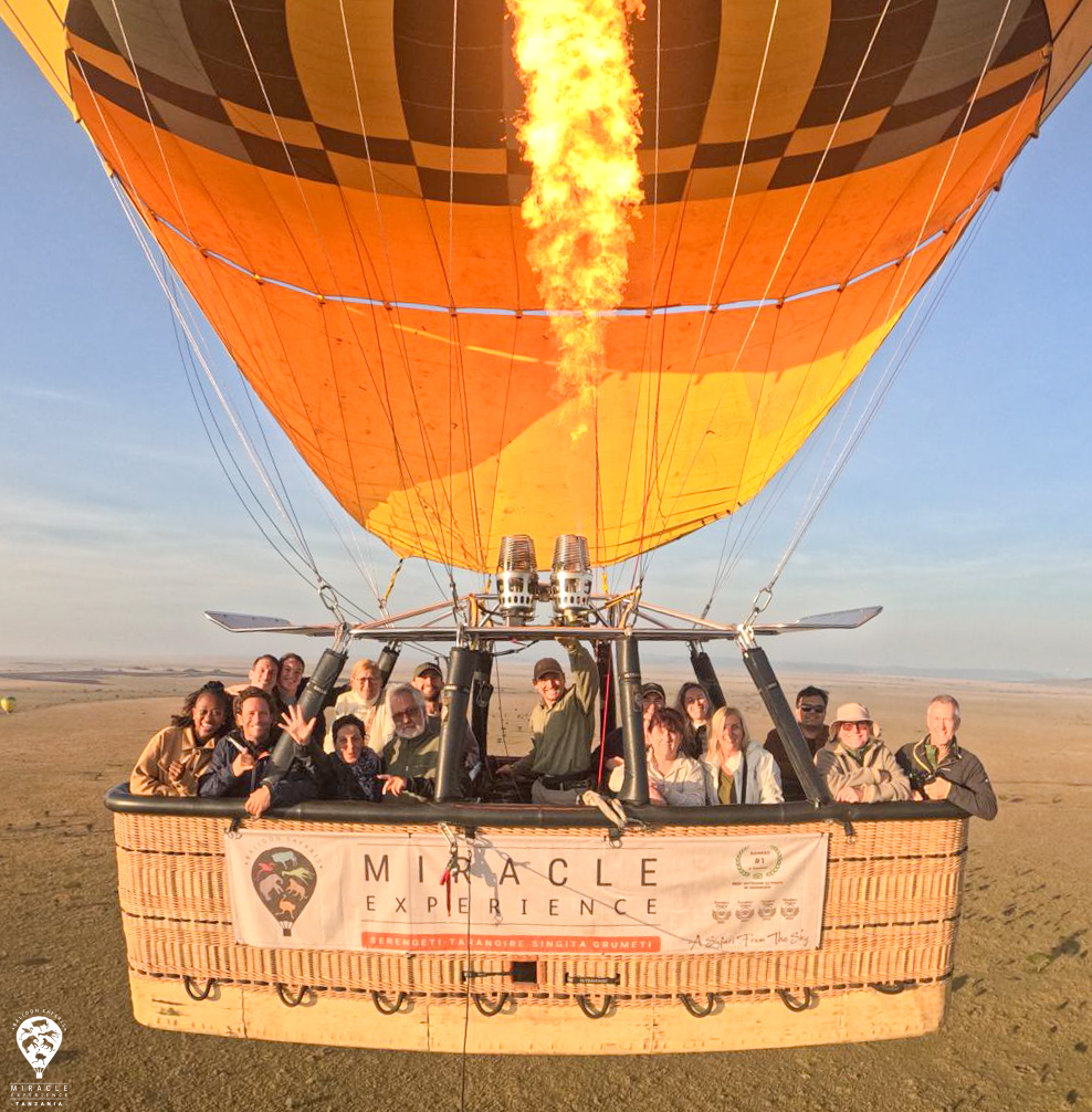 Travellers in a hot air balloon basket with the burner lit above the plains