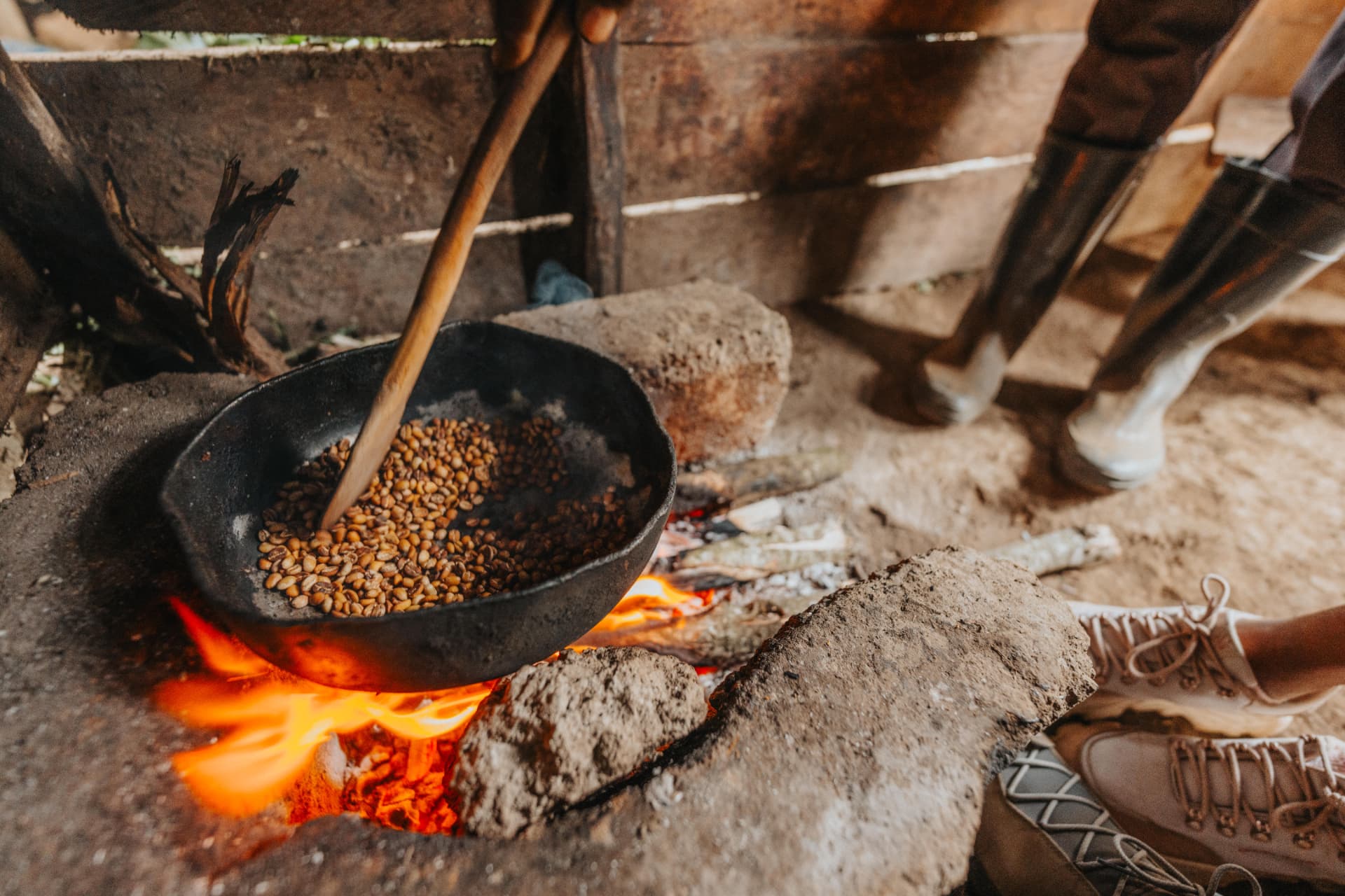 Coffee beans roasting in a pan over an open fire