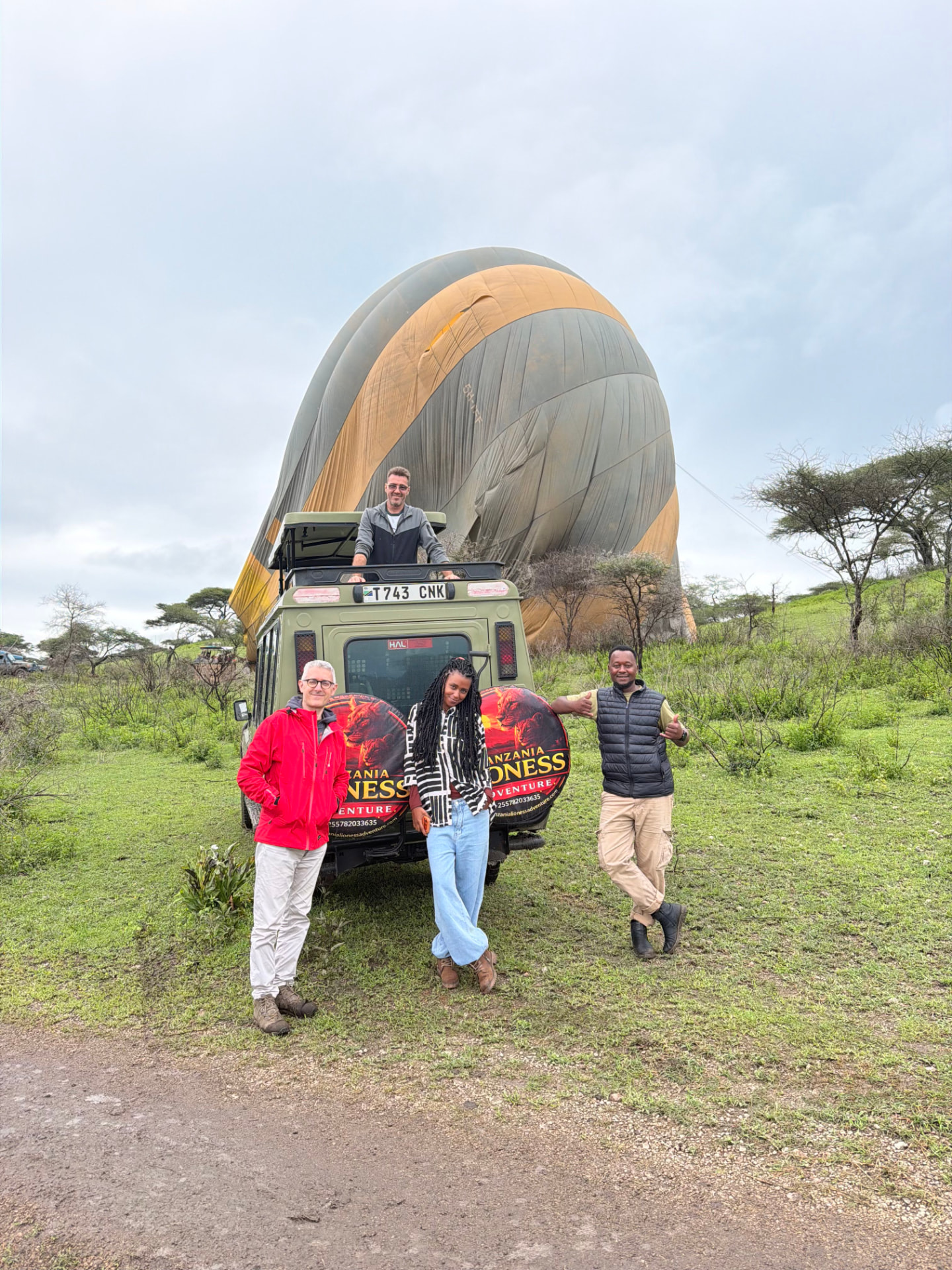 Guests and guides beside a Tanzania Lioness Adventure vehicle in front of a hot air balloon