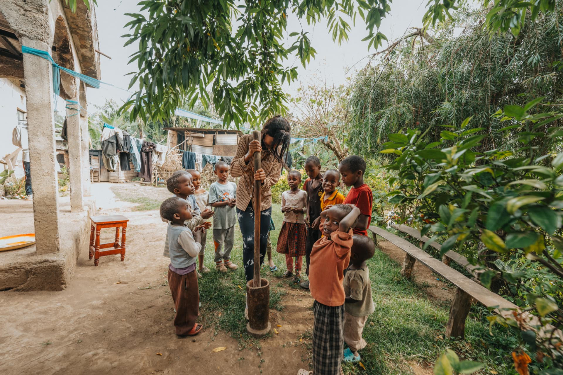 Noreen grinding coffee with children gathered around in a village garden