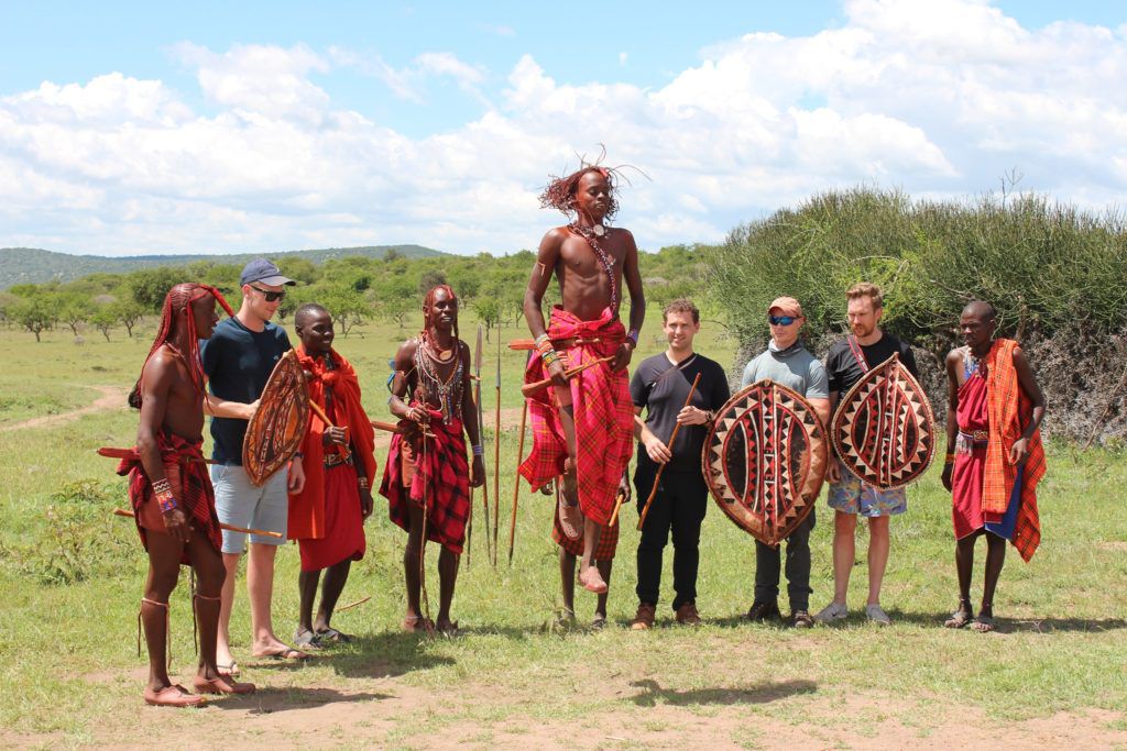 Travellers standing with Maasai guides in the open savannah
